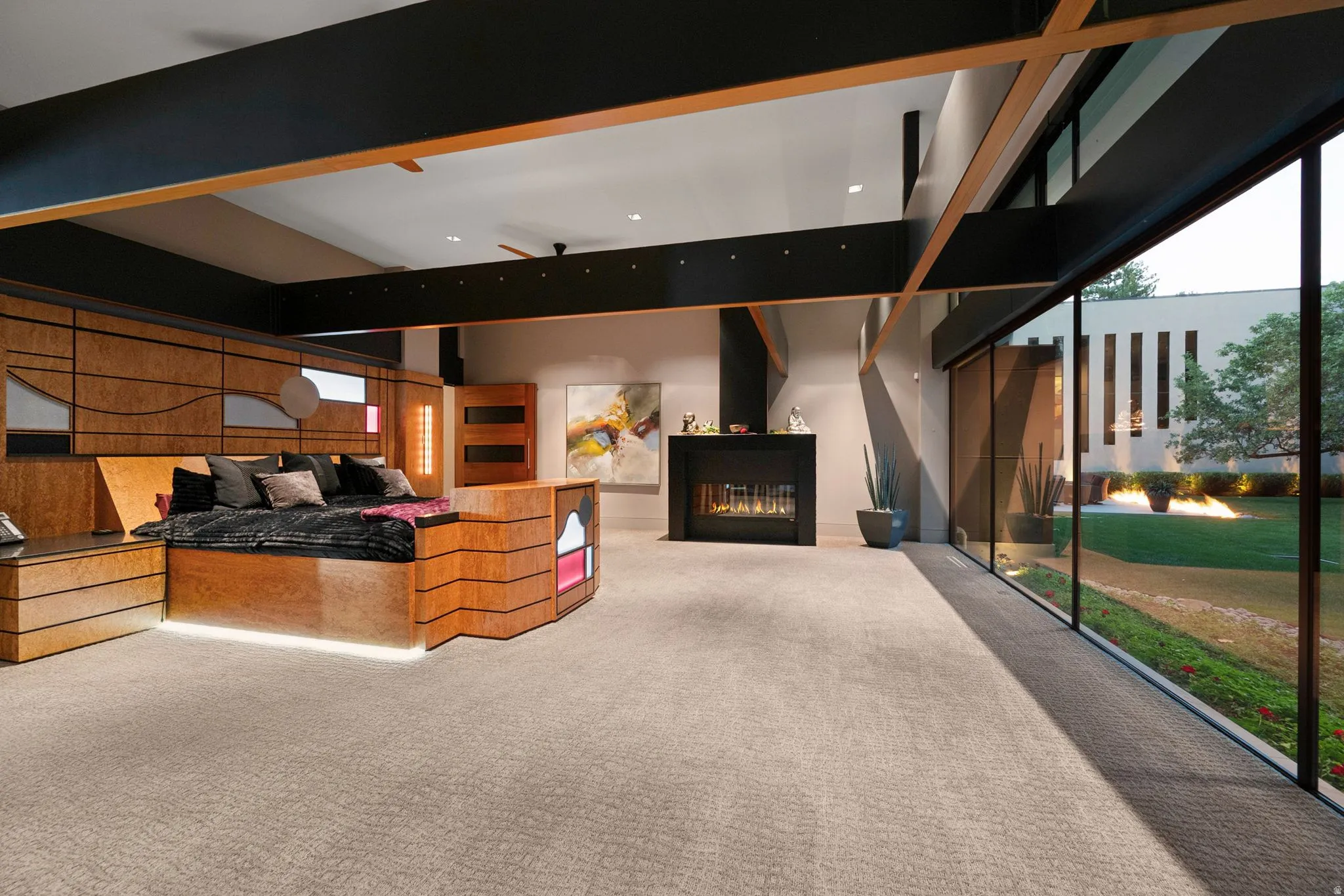 Floor-to-ceiling glass wall, built-in fireplace, recessed lighting, and a built-in custom wood bed frame with integrated lighting