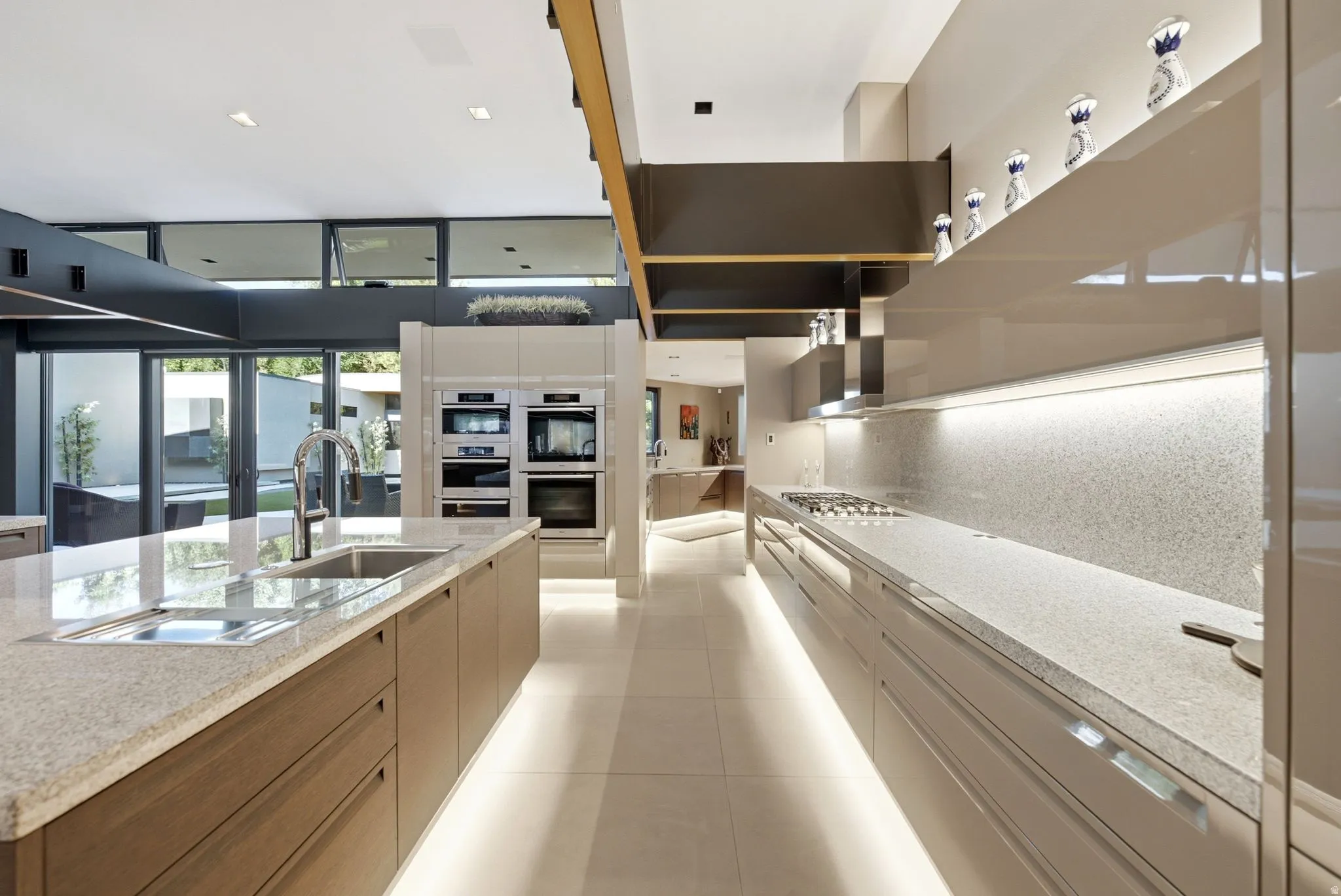 Gourmet kitchen with double wall ovens, built-in cooktop, under-cabinet lighting, and extensive counter space