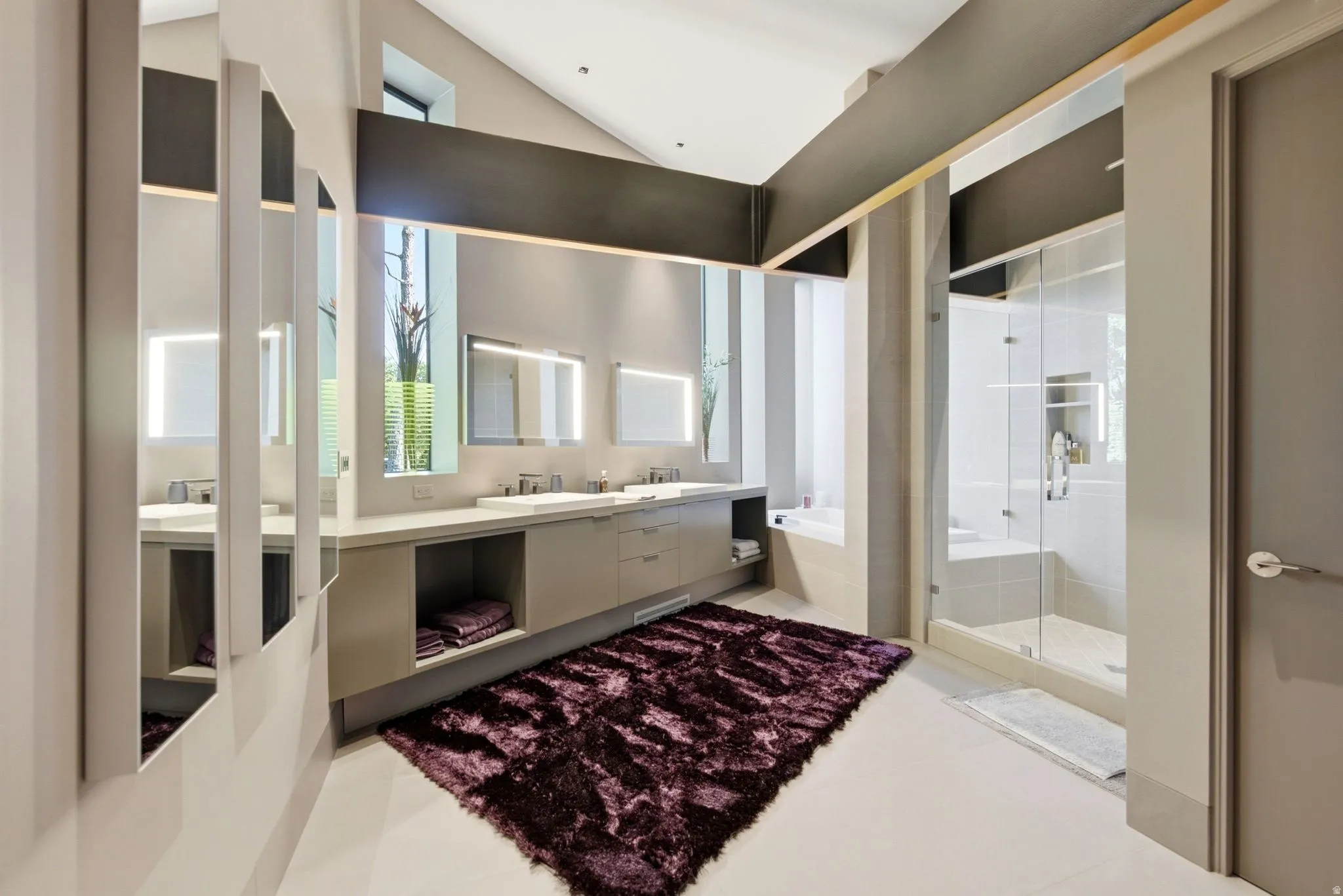 Vaulted ceiling with exposed beam, dual vanity with undermount sinks, frameless glass shower enclosure, built-in shower bench, and a standalone soaking tub