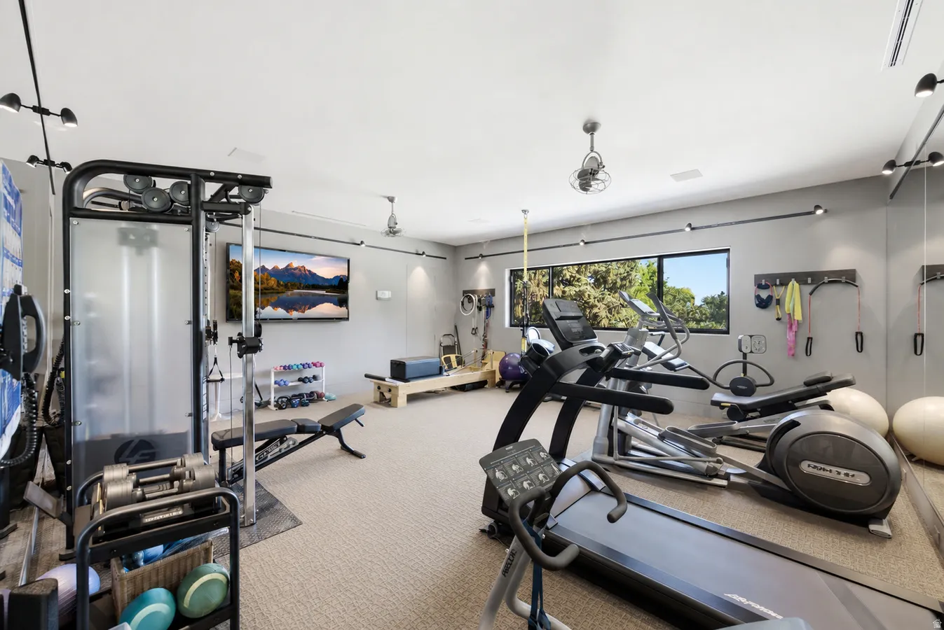 Dedicated fitness room featuring recessed lighting, track lighting, ceiling fans, and a large horizontal window