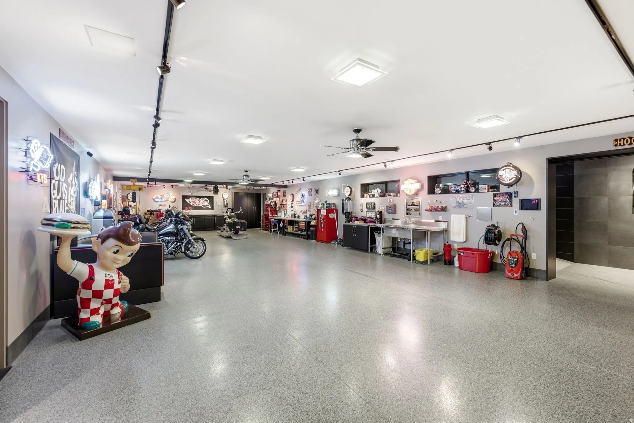 Spacious garage featuring polished concrete flooring, overhead lighting, and ample storage cabinetry along perimeter walls