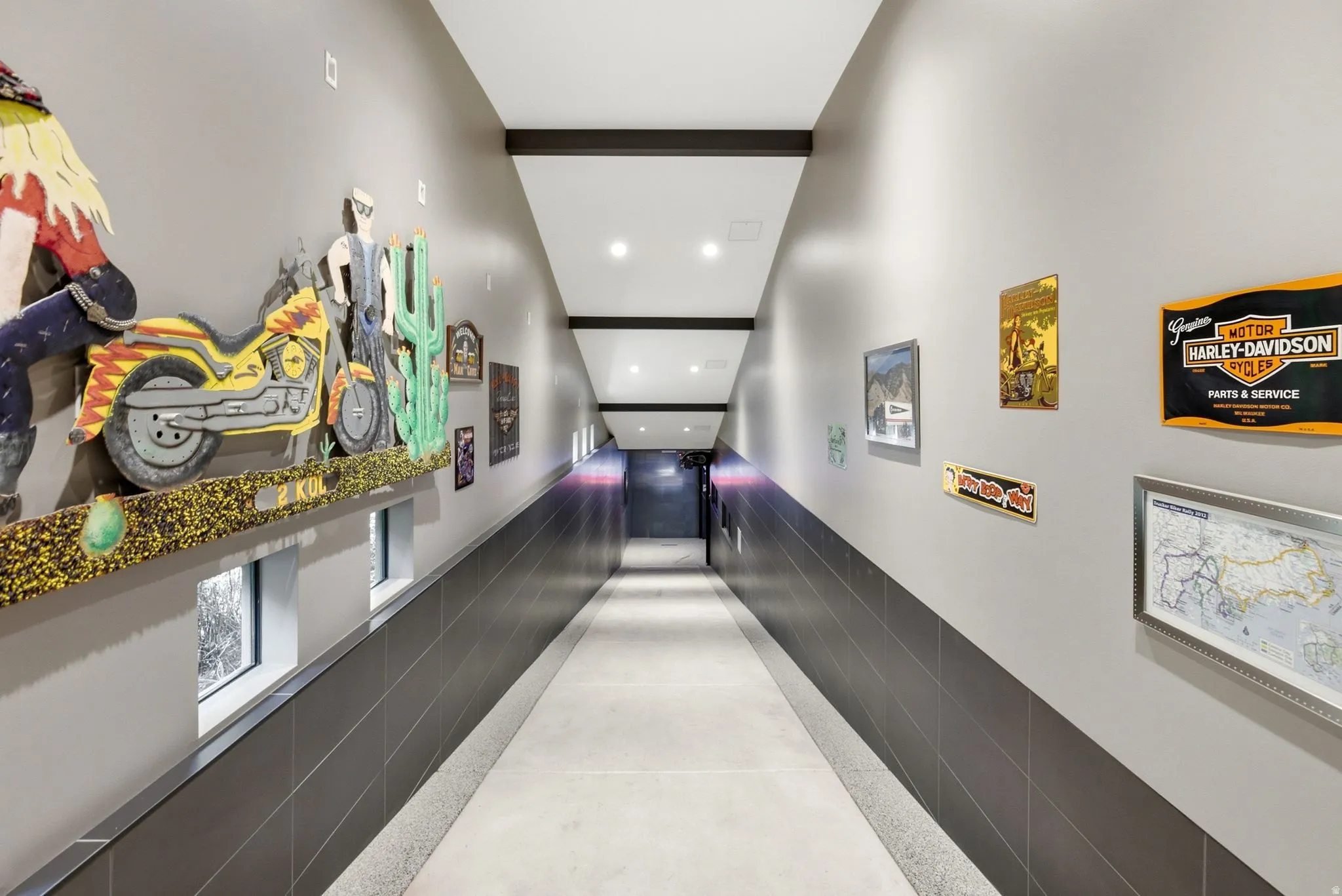Long corridor with overhead beam accents, recessed lighting, and a lower wall finished with dark tile