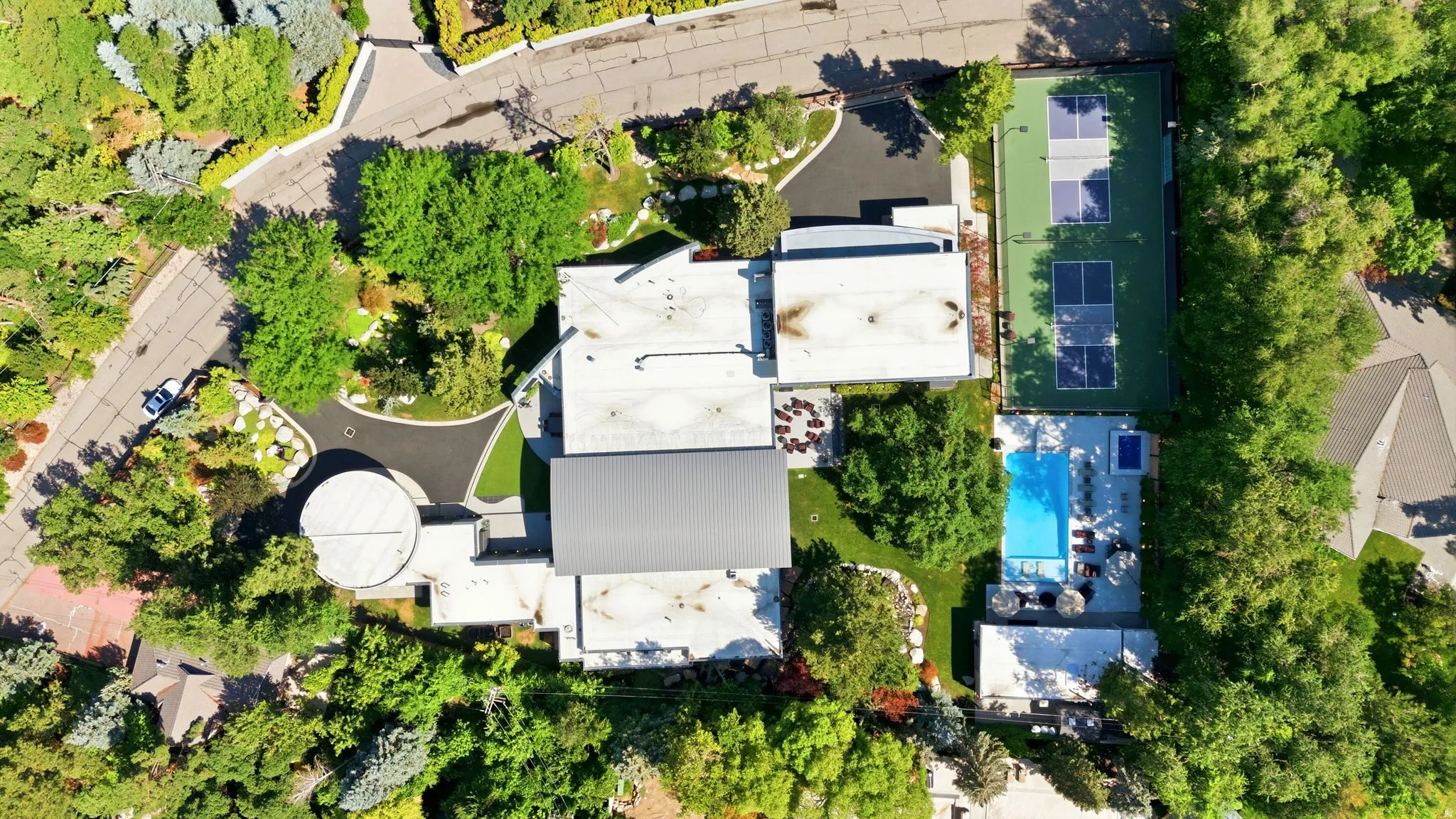 Asphalt driveway, tennis court, swimming pool, and extensive surrounding greenery
