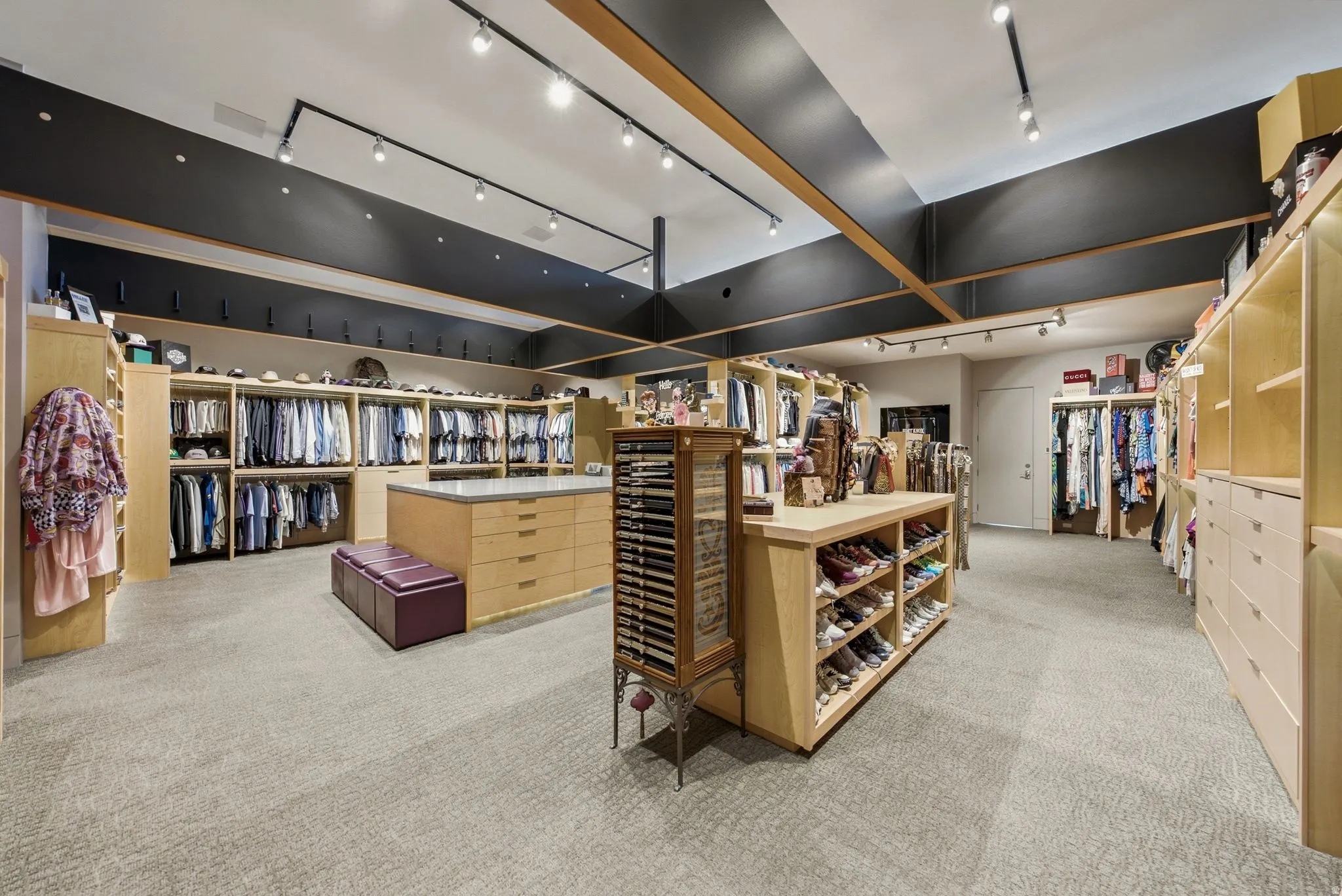Expansive dressing room featuring track lighting, light wood cabinetry, and a central island with integrated drawers
