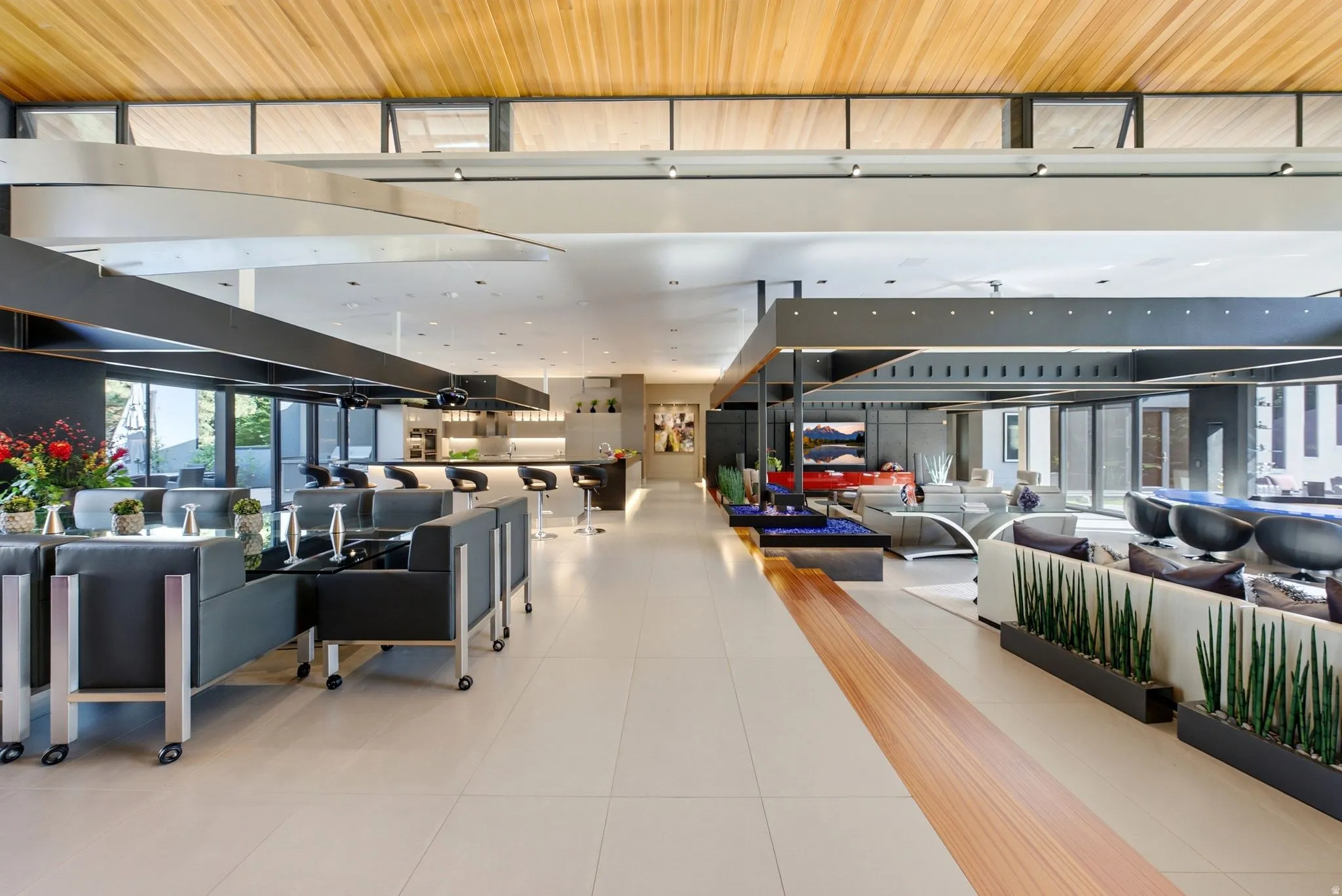 Expansive open-concept interior with a wood-finish ceiling, light-toned tile flooring, and a linear fireplace feature