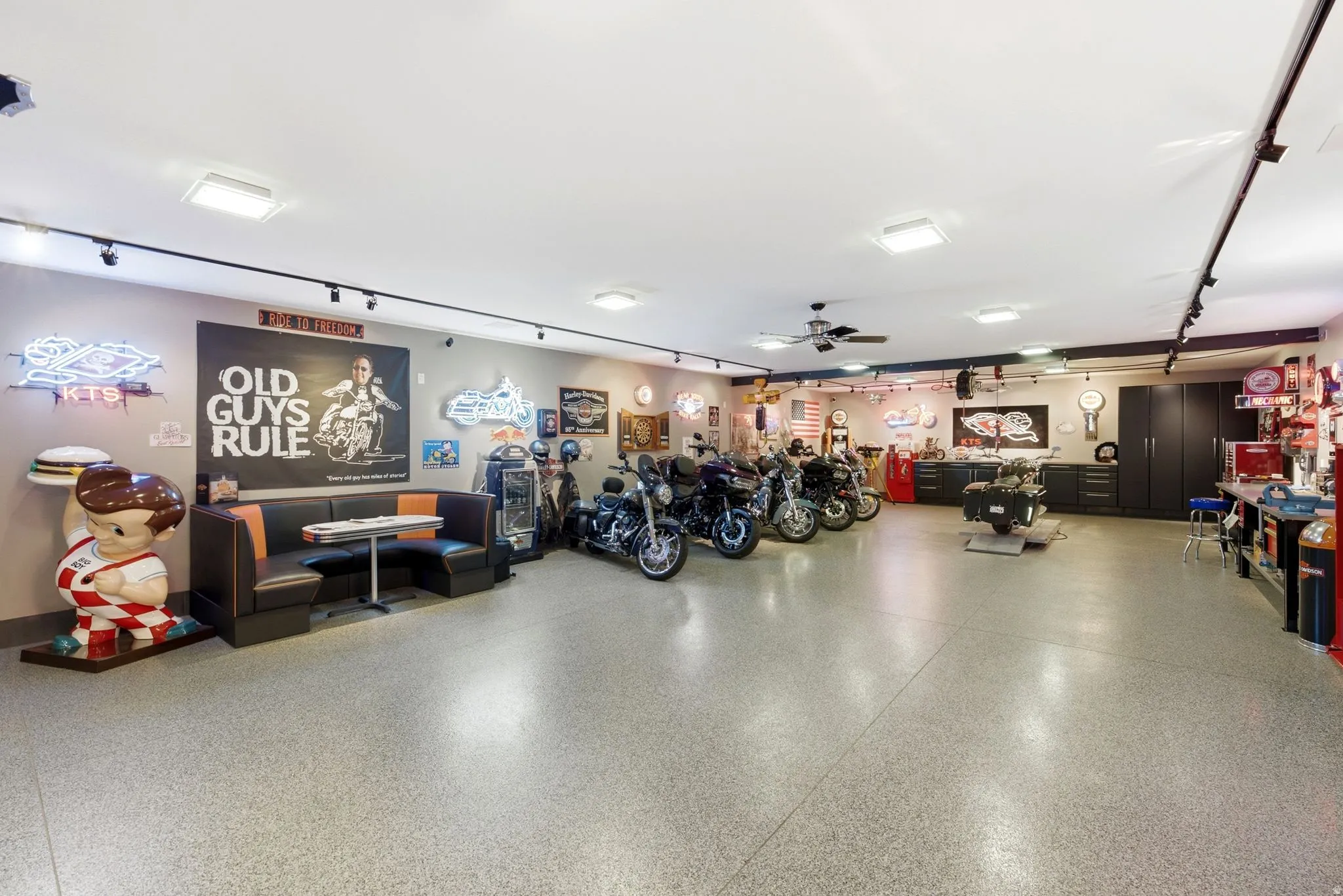 Spacious garage with light gray flooring, track lighting, and built-in dark cabinetry