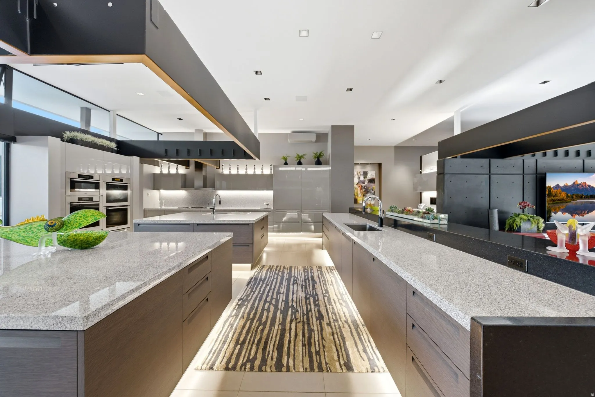 Expansive kitchen featuring multiple islands with light-toned countertops, integrated stainless steel appliances, abundant cabinetry, and recessed lighting
