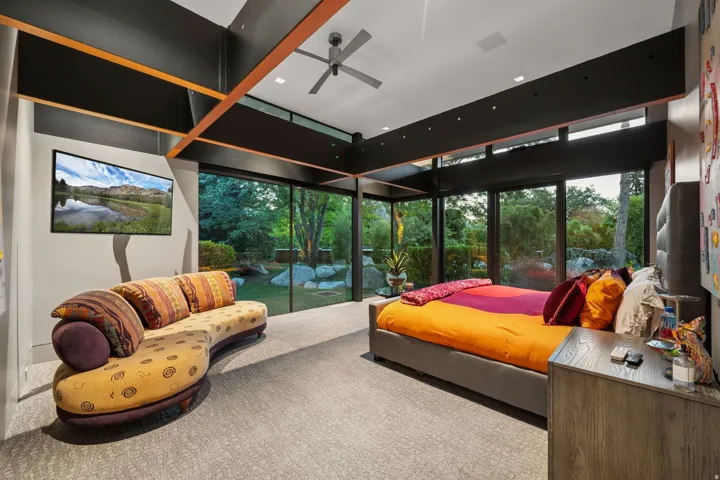 Floor-to-ceiling windows, exposed structural beams, ceiling fan, recessed lighting, and wall-mounted television