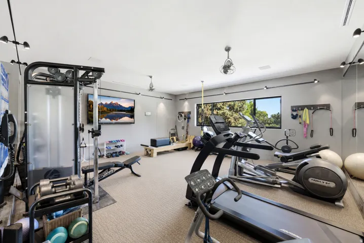 Dedicated fitness room featuring recessed lighting, track lighting, ceiling fans, and a large horizontal window