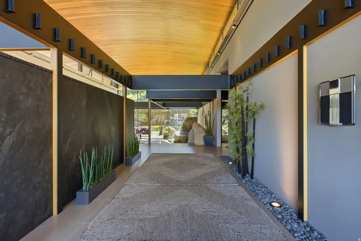 Covered exterior walkway featuring a wood-finish ceiling, exposed structural beams, and integrated lighting