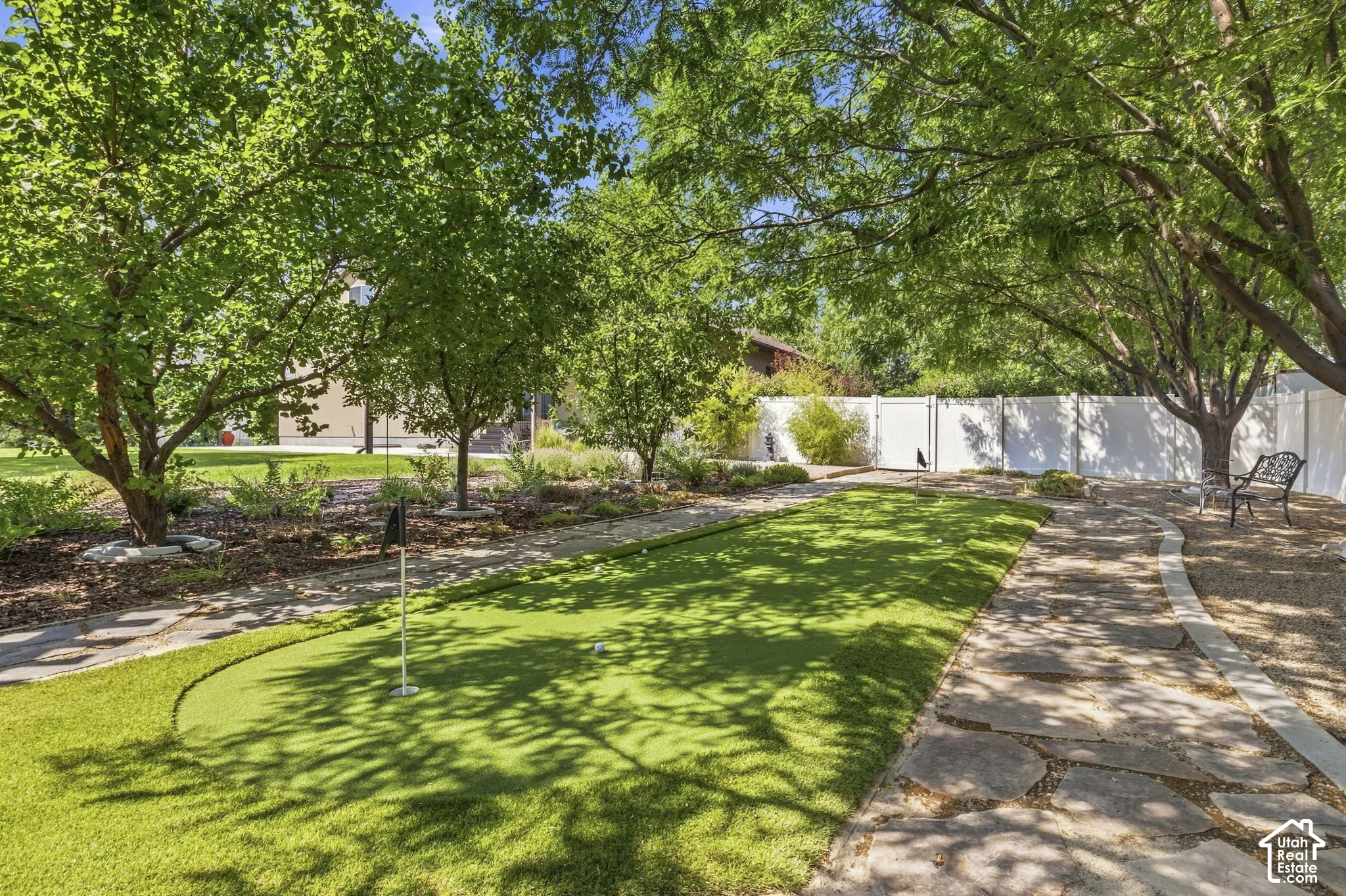 Private backyard with a putting green, mature trees, a flagstone pathway, and a privacy fence