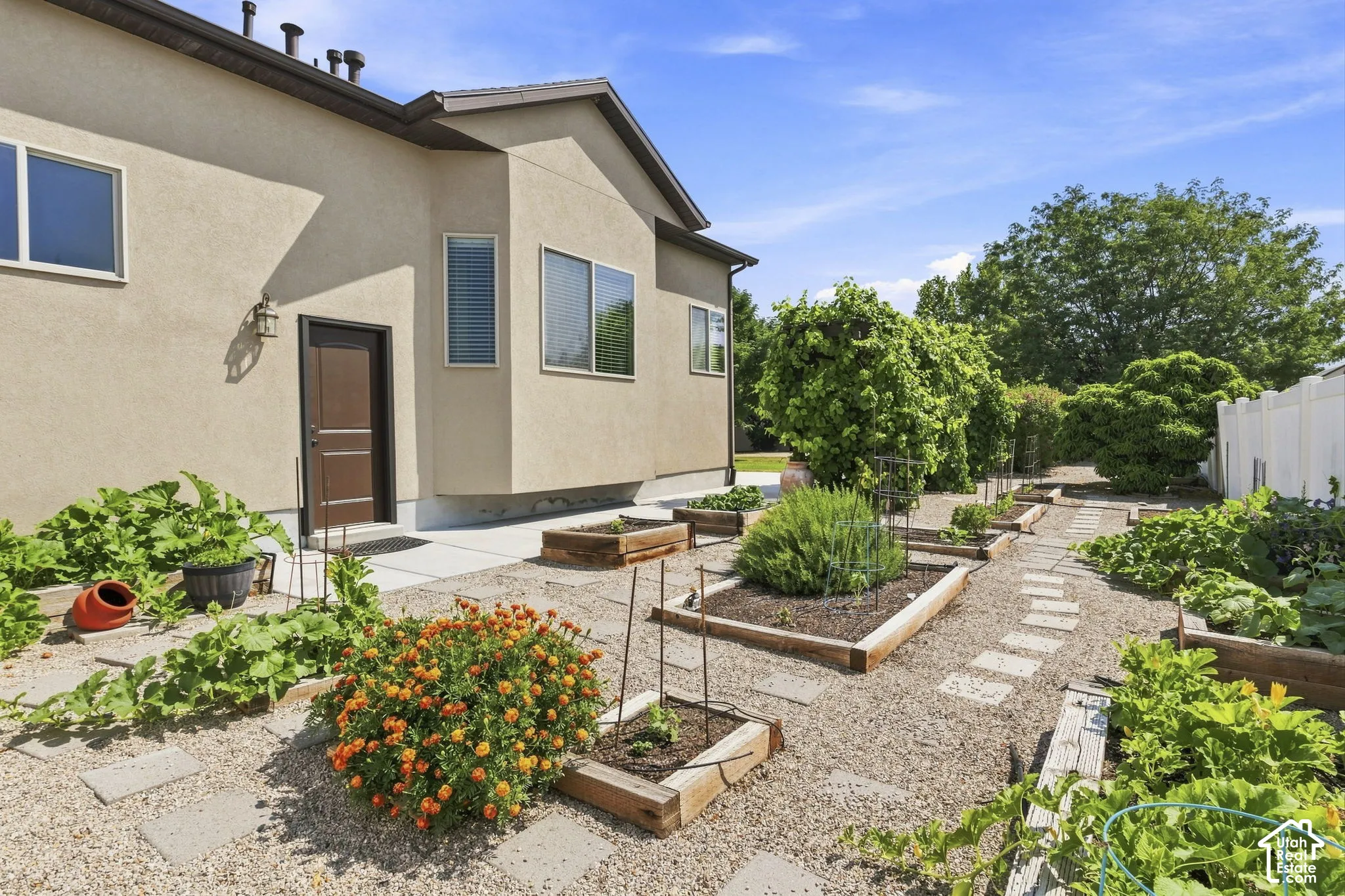 Expansive backyard featuring gravel pathways, raised garden beds, and mature trees