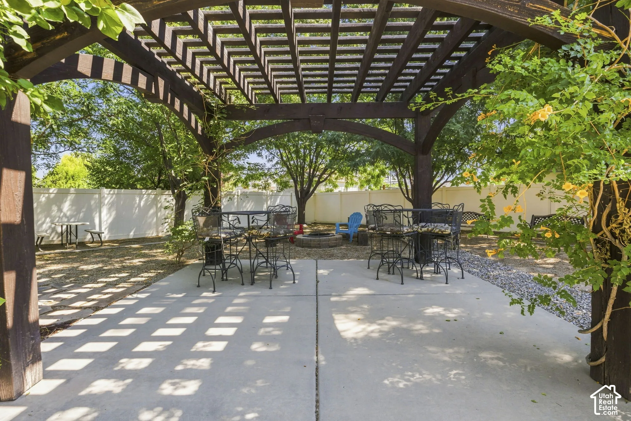 Expansive concrete patio with a dark wood pergola, gravel landscaping, and a white privacy fence