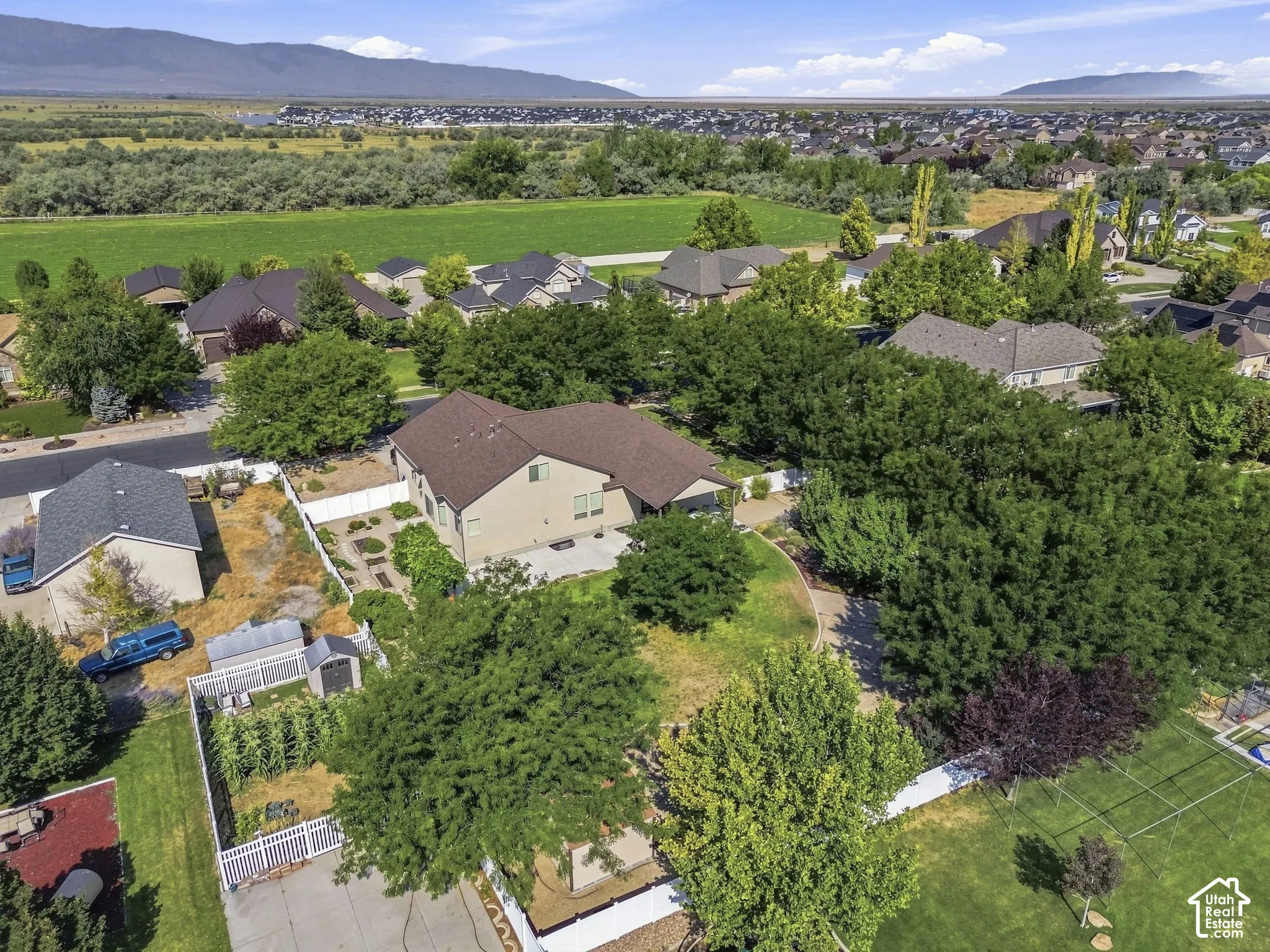 Aerial perspective showcasing a residential property with a brown-shingled roof and tan exterior, surrounded by mature trees