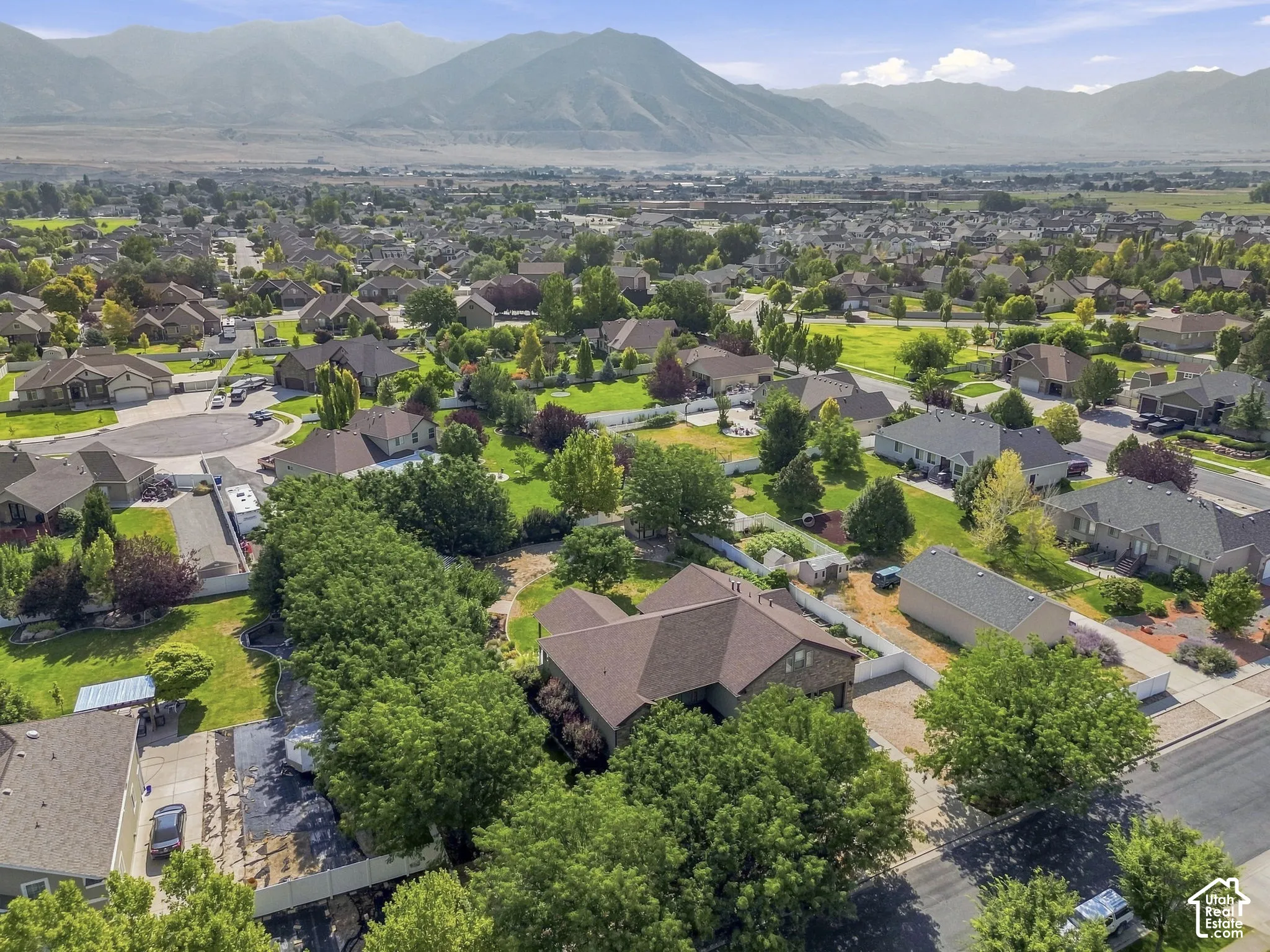 Expansive residential area featuring numerous single-family homes, mature trees, and mountainous terrain