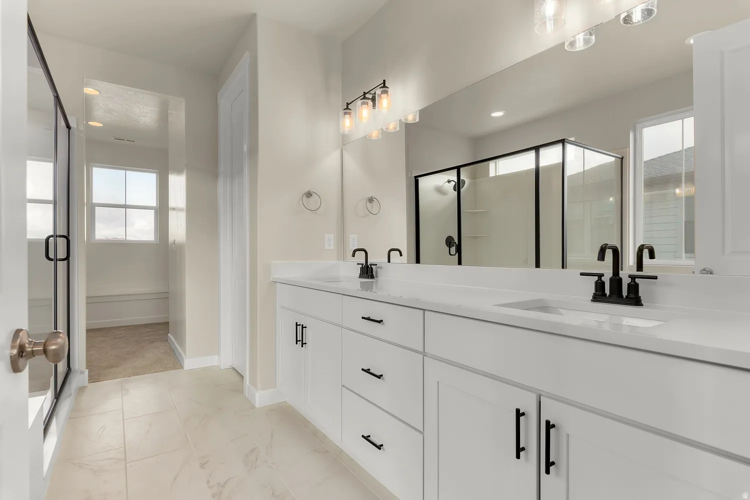 Dual vanities with white countertops, black-finish faucets, and under-sink storage