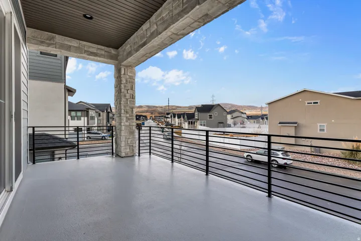 Expansive covered balcony featuring a stone pillar, black metal railing, and wood-finish soffit