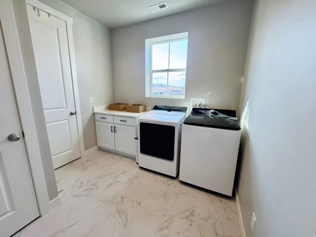 White shaker-style cabinetry with dark hardware, a light-toned countertop, and patterned tile flooring