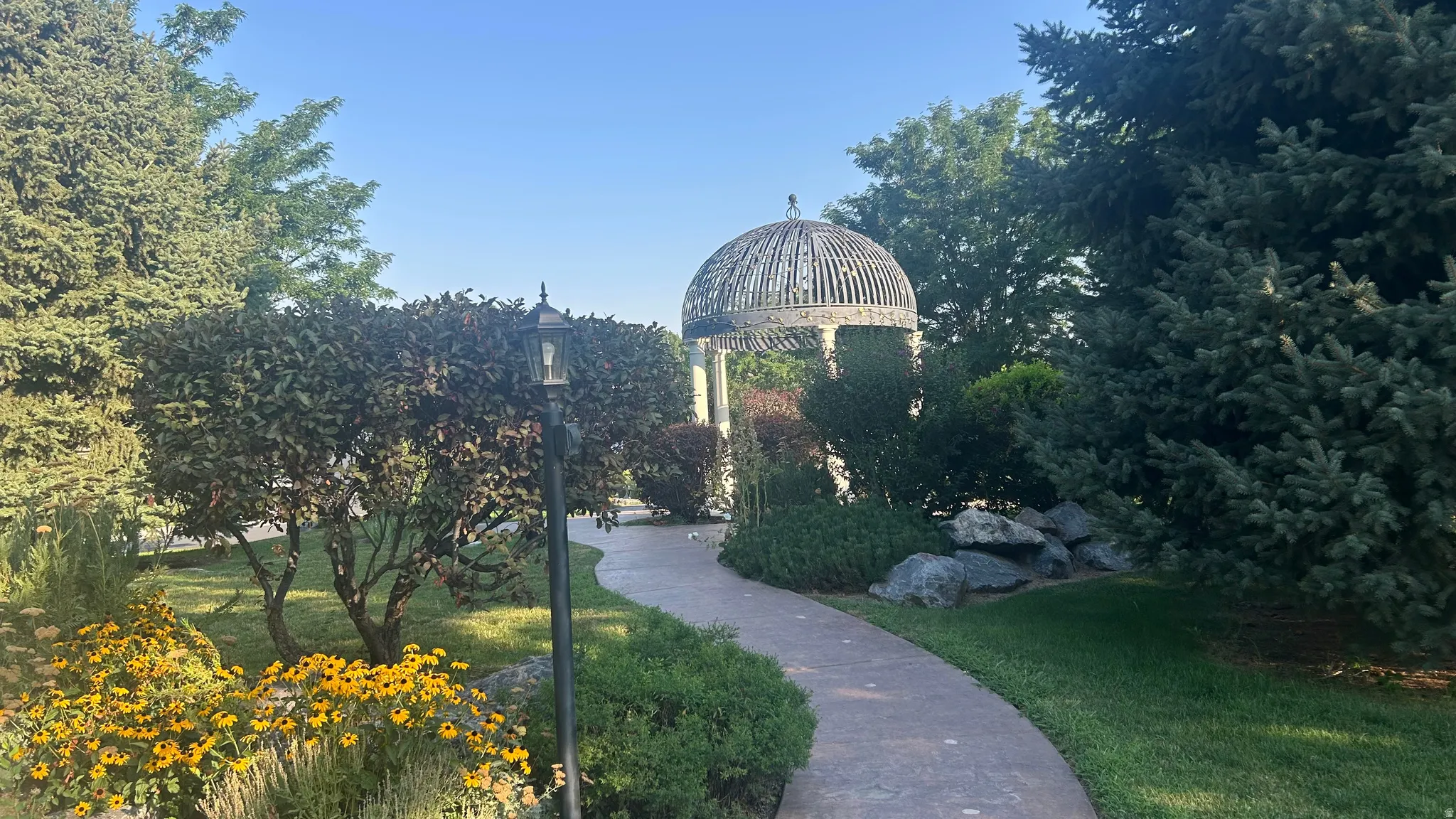 Curved pathway leading to gazebo with sitting area.