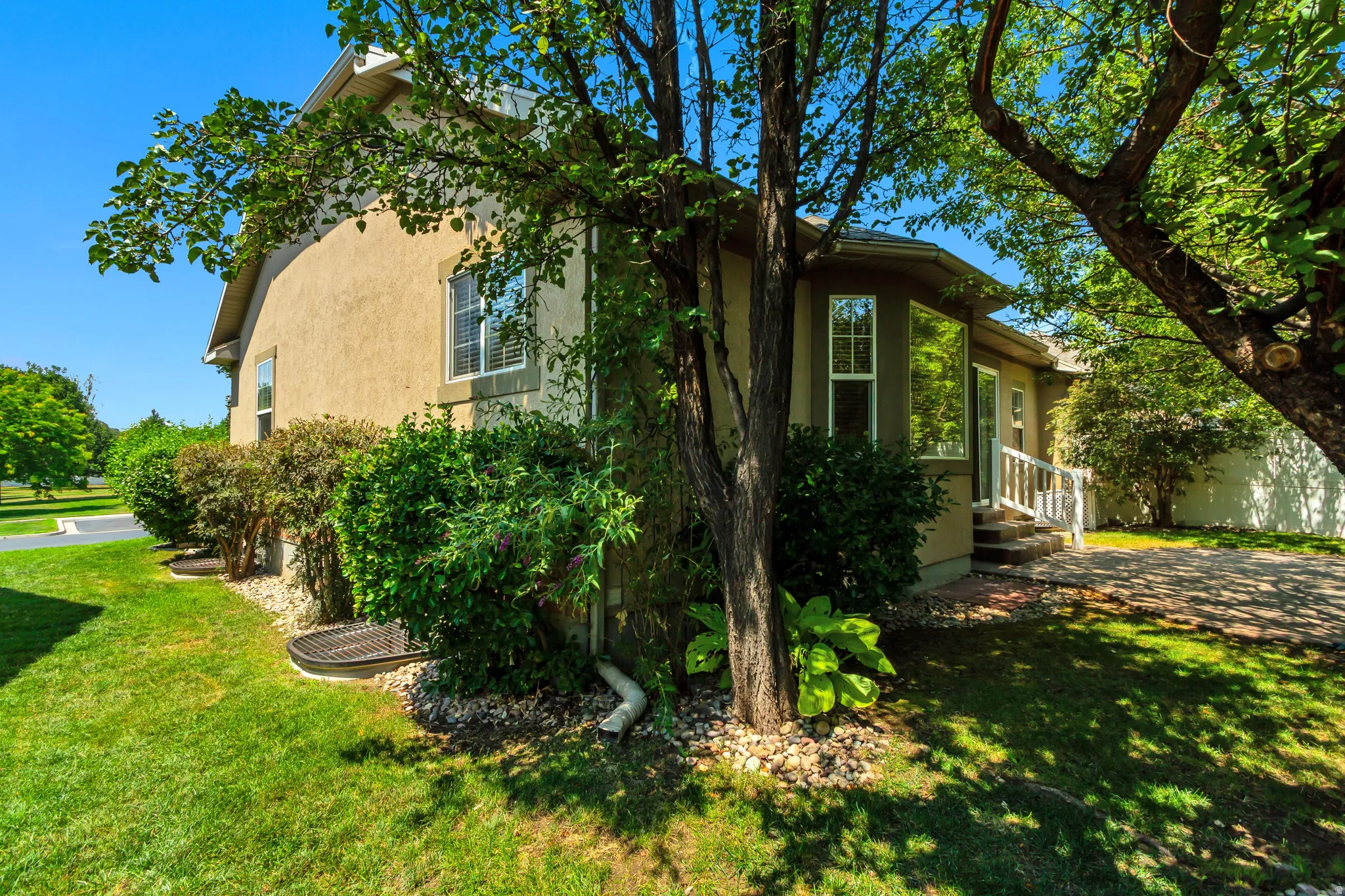 Mature landscaping with dappled shade from large trees surrounding home.