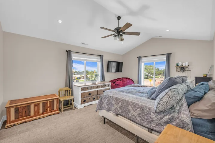 Vaulted ceiling with a ceiling fan, recessed lighting, and dual windows
