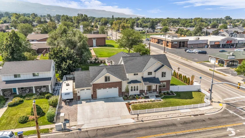 Multi-level residence featuring a three-car garage, white picket fence, and a stone and siding exterior