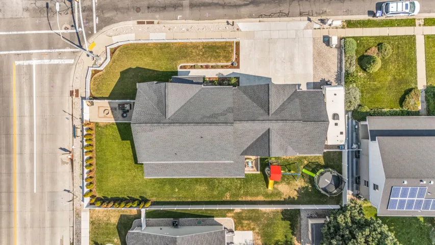 Gabled roofline, concrete driveway, corner lot, mature landscaping, and privacy fencing