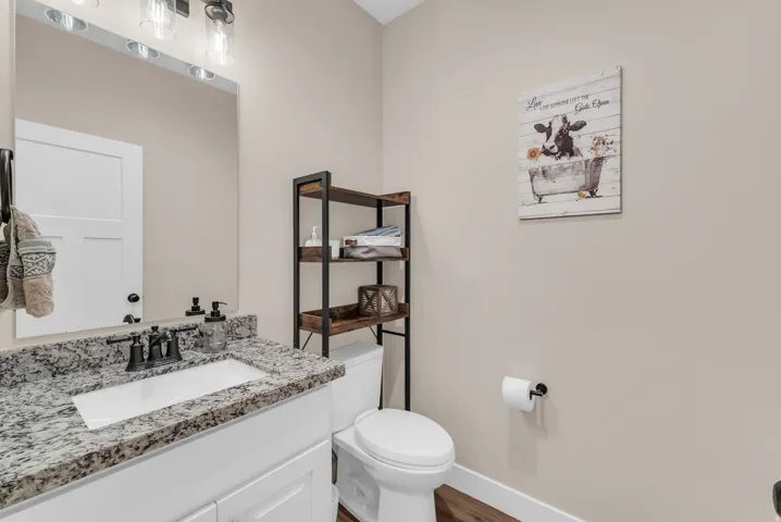 Main level 1/2 bath with bathroom vanity with a granite countertop, undermount sink, and matte black faucet