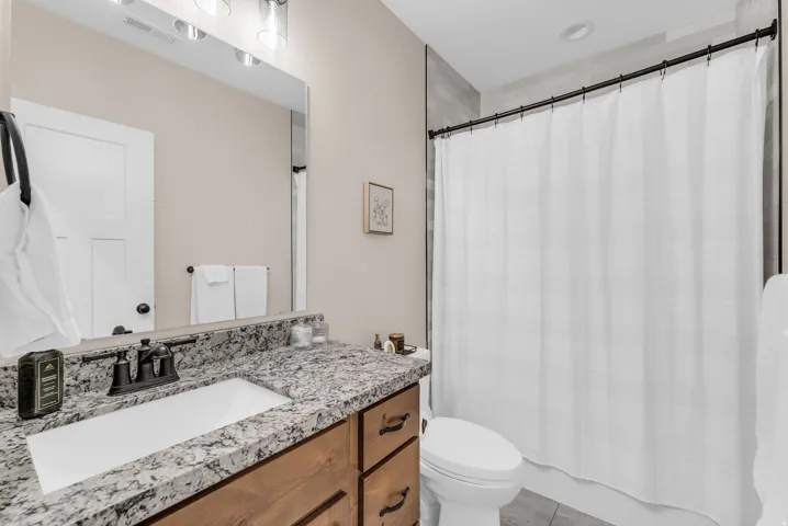 Vanity with a granite countertop, integrated rectangular sink, and dark bronze faucet