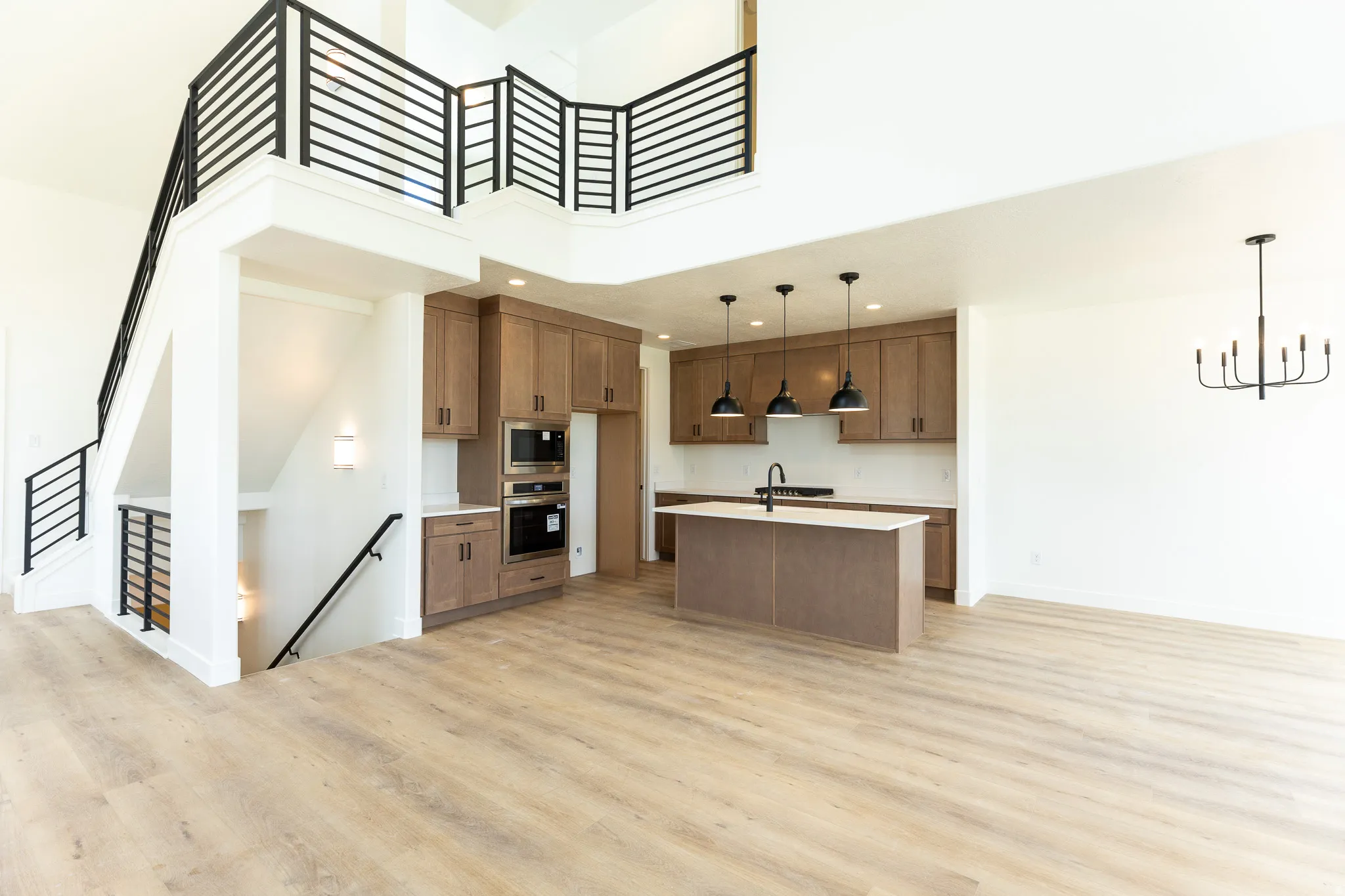 Open-concept living space featuring wood-finish flooring, a two-story ceiling, and a modern kitchen