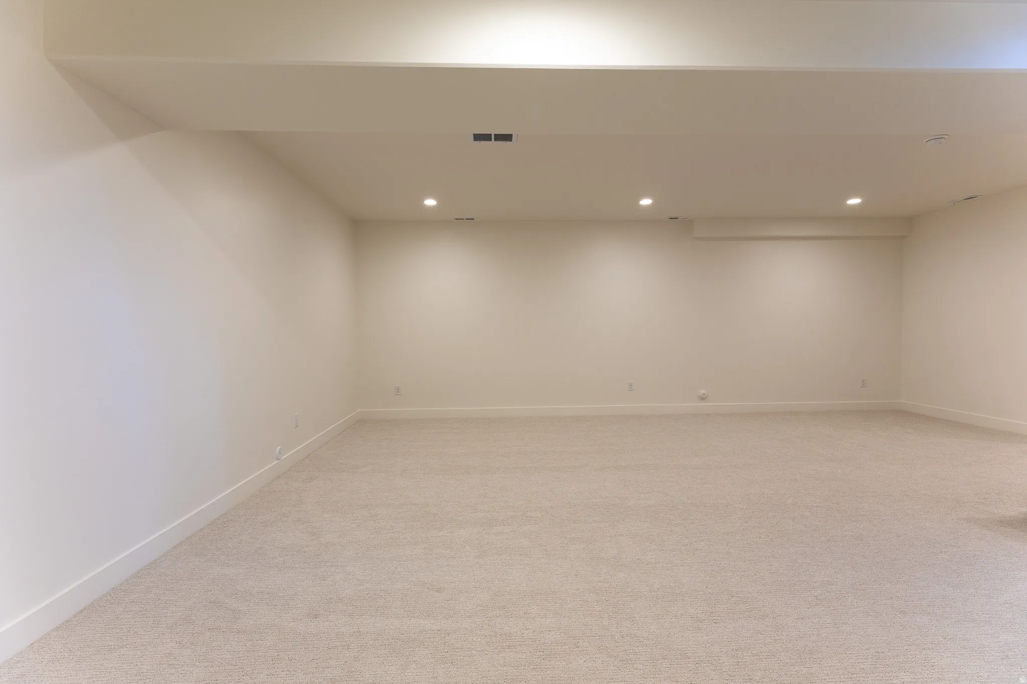 Expansive carpeted room featuring recessed lighting, light-toned walls, and white baseboards