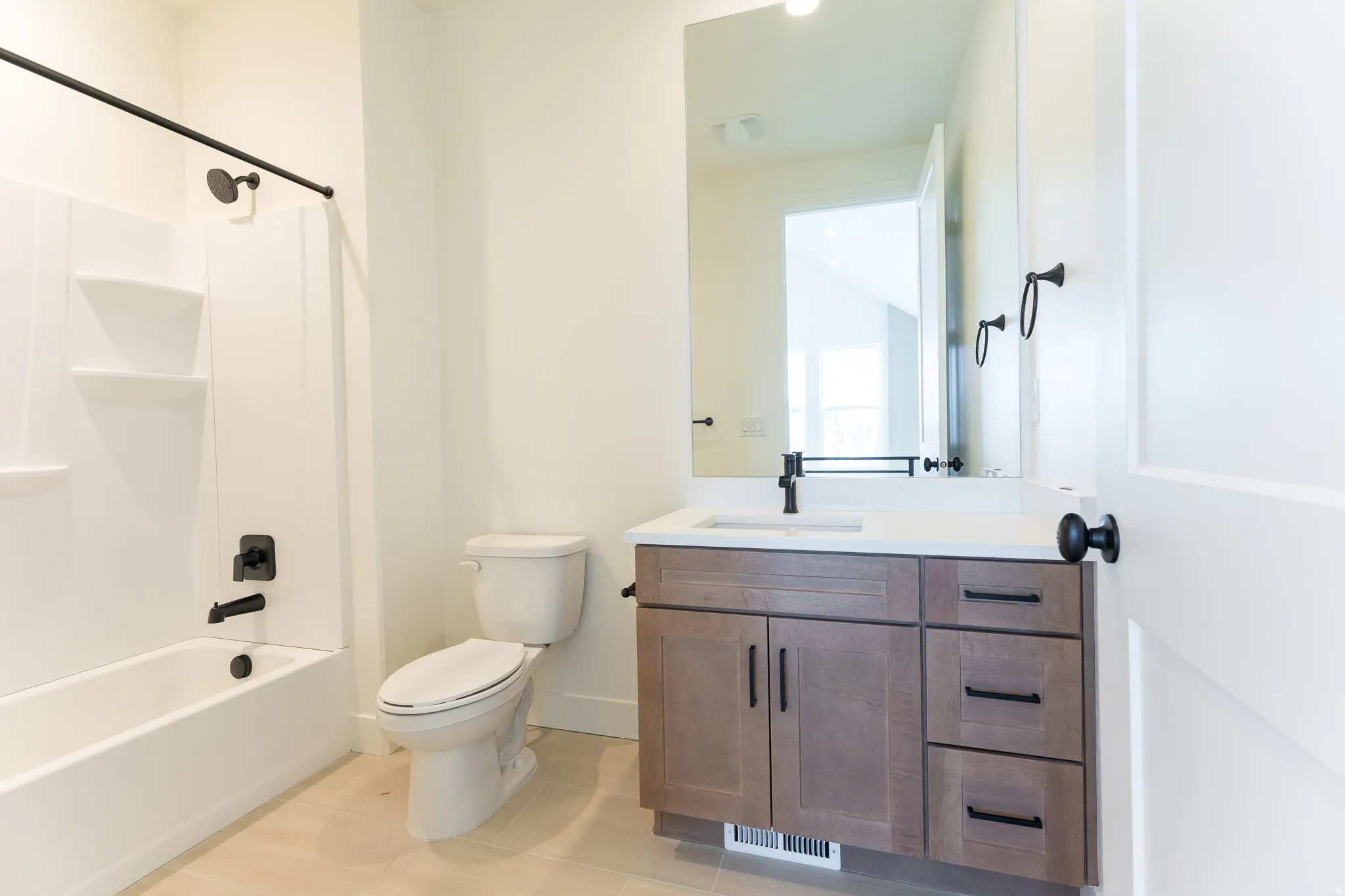 Bathroom featuring a contemporary vanity with a white countertop, an integrated sink, and matte black fixtures