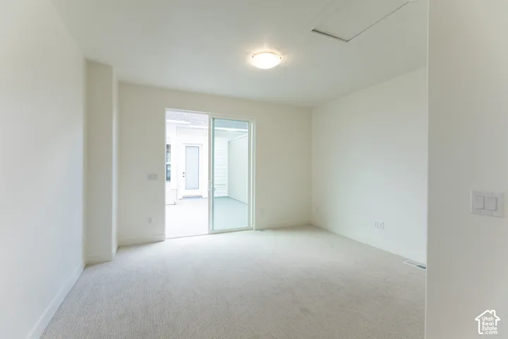 Bright room featuring light-toned carpeting and a sliding glass door leading to an outdoor patio