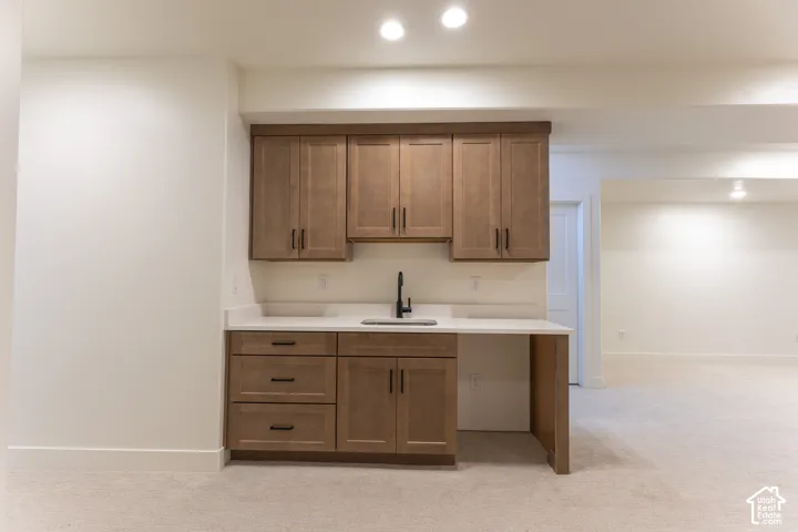 Built-in wet bar featuring wood cabinetry, white countertops, an undermount sink, and a matte black faucet