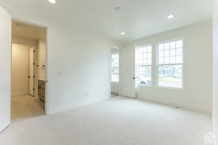 Spacious interior room with light-toned carpet flooring and white painted walls