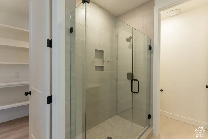 Glass-enclosed shower with matte black hardware, tiled walls, a built-in niche, and a mosaic tile floor