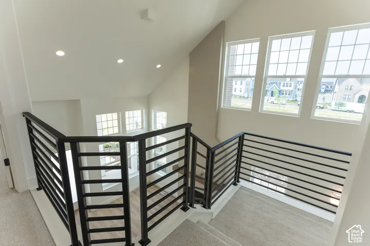 Upper landing featuring contemporary horizontal metal railings, multiple recessed ceiling lights, and three large grid-pane windows
