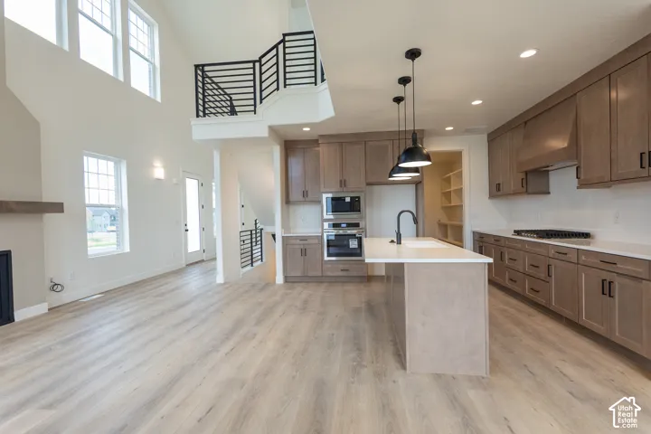 Open-concept living space featuring wood-finish flooring, a two-story ceiling with high windows, and a modern kitchen