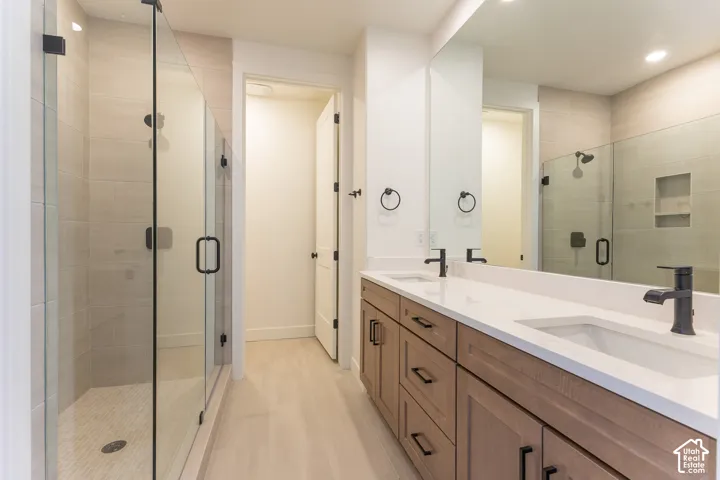 Contemporary bathroom featuring a double vanity with stone countertops, undermount sinks, and matte black fixtures