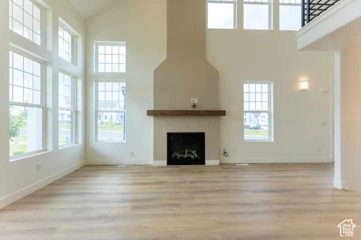 Vaulted ceilings, wood-finish flooring, and a fireplace with a wood mantle