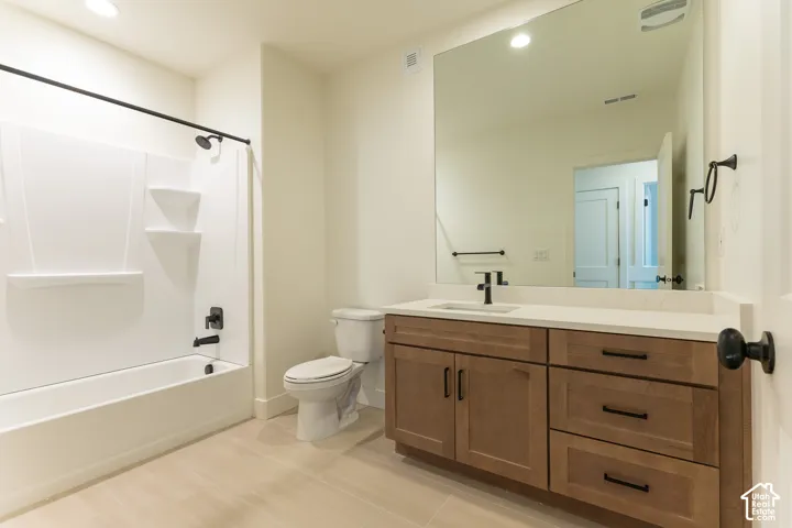 Bathroom featuring a vanity with wood-finish cabinetry, a light-toned countertop, and a rectangular undermount sink with matte black fixtures