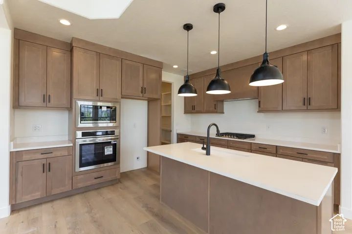 Kitchen featuring a central island with white countertop, black faucet, and three pendant lights