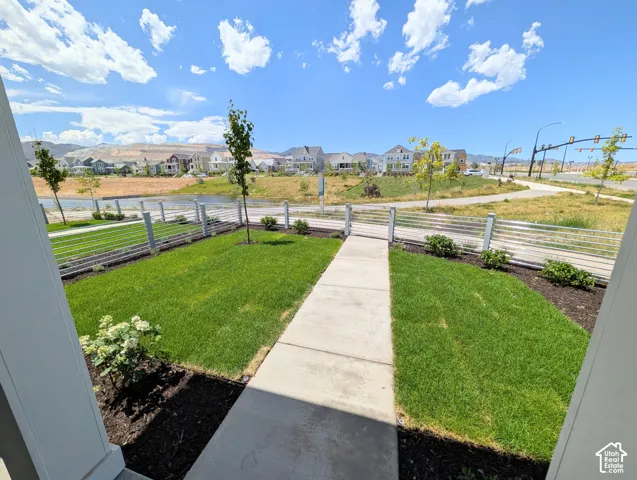 Front yard with a concrete walkway, manicured lawn, and planted flower beds