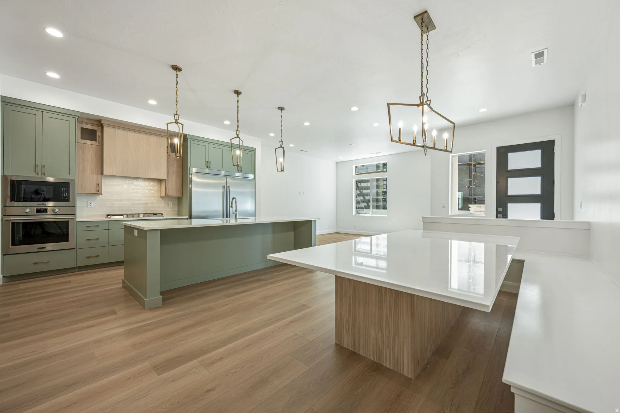 Gourmet kitchen with two-tone cabinetry, integrated stainless steel appliances, and a central island with a waterfall countertop