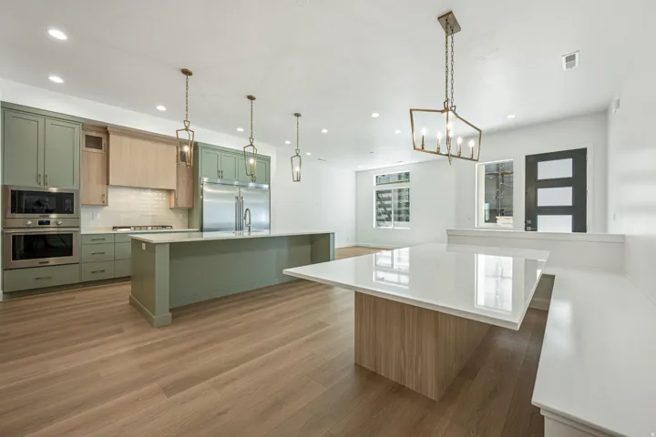 Gourmet kitchen with two-tone cabinetry, integrated stainless steel appliances, and a central island with a waterfall countertop