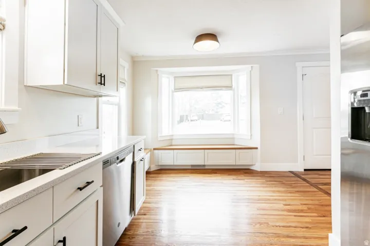 White cabinetry, stainless steel appliances, and a bay window with integrated bench seating