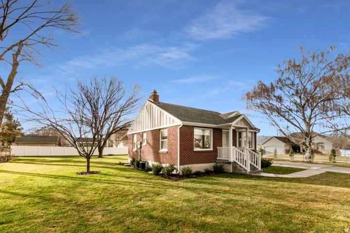 Brick exterior, white siding accents, covered front porch, white porch railings, green landscaping