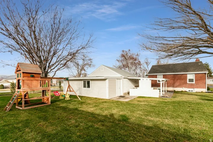 Expansive green lawn with a white siding extension and a red brick structure