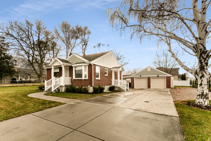 Brick exterior with siding accents, covered front porch, concrete walkway, detached two-car garage, and a concrete driveway