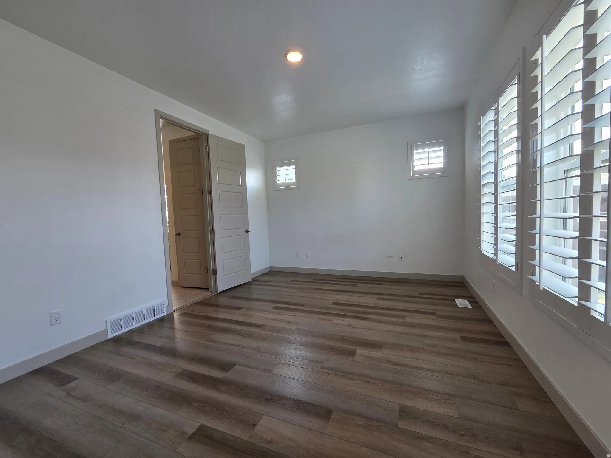 Wood-finish flooring, white walls, white window shutters, recessed lighting, and a white ceiling